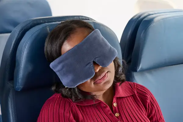 A person wearing the Lunya Washable Silk Sleep Mask on an airplane