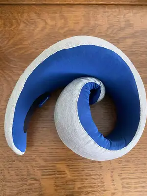 A person holding the Ostrich Pillow Go Neck Pillow on their neck