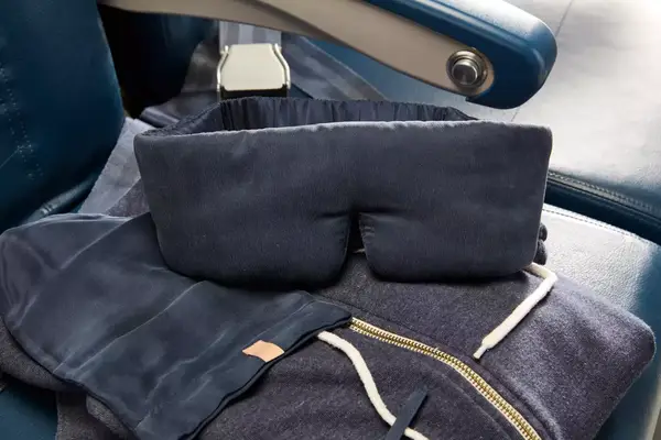 The Lunya Washable Silk Sleep Mask laid out on an airplane seat