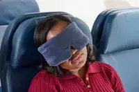 A person wearing the Lunya Washable Silk Sleep Mask on an airplane