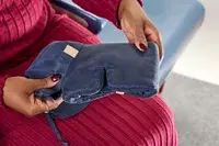 A person removing the Lunya Washable Silk Sleep Mask from the travel pouch