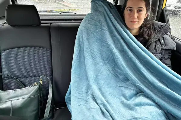 Person using the PAVILIA Travel Blanket and Pillow in the backseat of a car