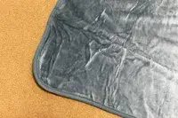 Corner of the PAVILIA Travel Blanket and Pillow displayed on a tan surface