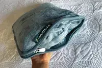 Hand holding a PAVILIA Travel Blanket zipped in its carrying case