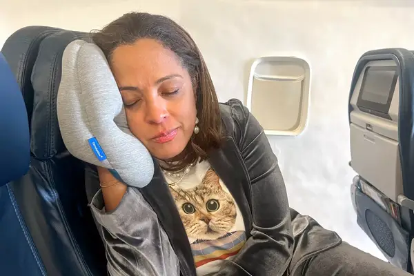 Closeup of a person using the Ostrichpillow Mini Handy Pillow on an airplane