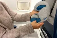 A person holding the Ostrichpillow Mini Handy Pillow on an airplane