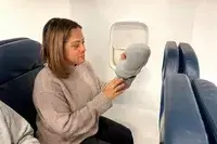 A person holding the Ostrichpillow Mini Handy Pillow on an airplane