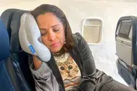 Closeup of a person using the Ostrichpillow Mini Handy Pillow on an airplane