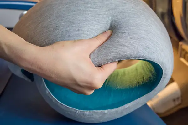 A close-up of the Ostrich Pillow Go Neck Pillow in a person