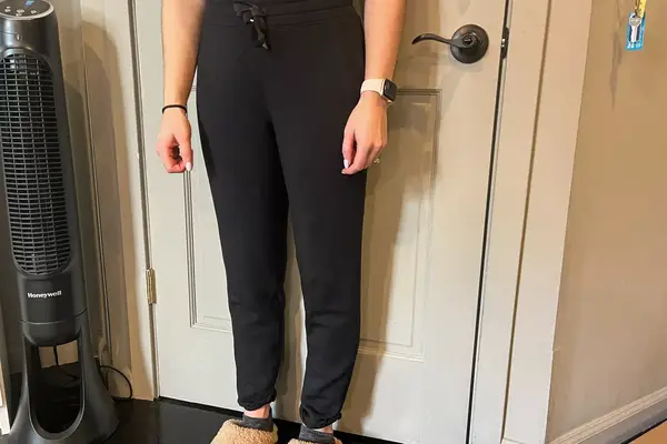 A person wears the Spanx AirEssentials Tapered Pant inside a house