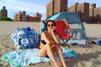 A person sitting on the Bay Laurel Turkish Beach Towel with Travel Bag