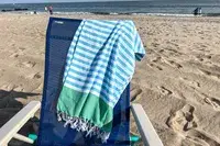The Bay Laurel Turkish Beach Towel with Travel Bag on a chair