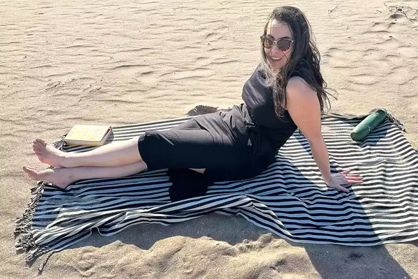A person sitting on the Fairmont Turkish Linen Towel on the beach