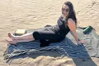 A person sitting on the Fairmont Turkish Linen Towel on the beach