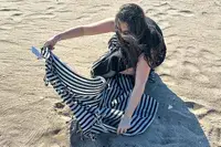 A person spreading the Fairmont Turkish Linen Towel on the beach