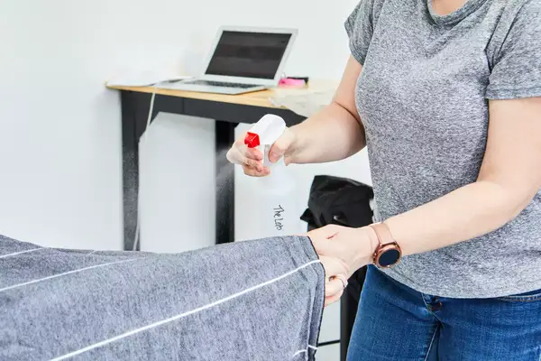 A person spraying the Cacala 100% Organic Cotton Pestemal Turkish Bath Towel with a solution