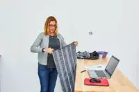A person holding a Cacala 100% Organic Cotton Pestemal Turkish Bath Towel near a wooden table