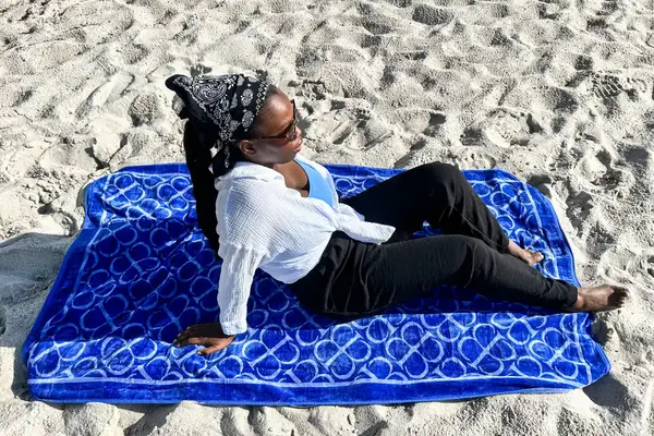 A person laying on the Boll & Branch The Beach Towel on sand