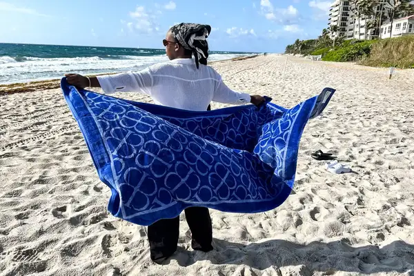 A person fanning out the Boll & Branch The Beach Towel