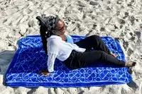 A person laying on the Boll & Branch The Beach Towel on sand