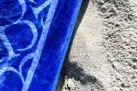A close-up of the Boll & Branch The Beach Towel on sand