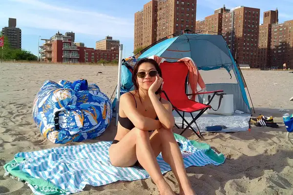 A person sitting on the Bay Laurel Turkish Beach Towel with Travel Bag