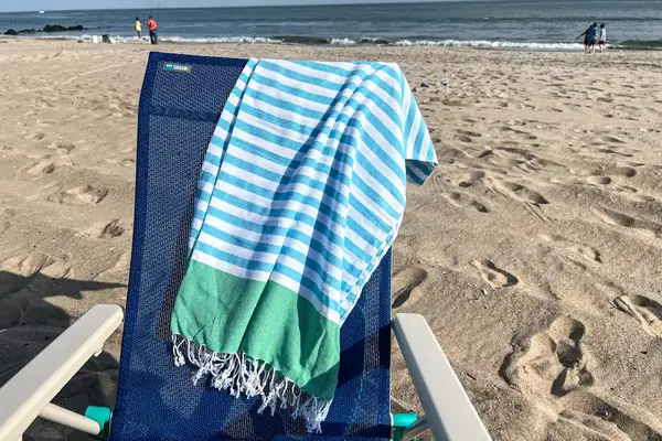 The Bay Laurel Turkish Beach Towel with Travel Bag on a chair