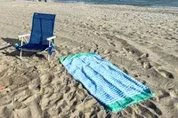 The Bay Laurel Turkish Beach Towel on sand next to a beach chair