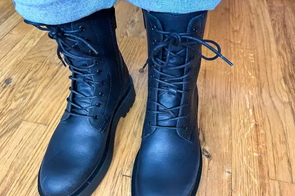 A person stands on a wooden floor while wearing the Thursday Boot Co. Quest Boots