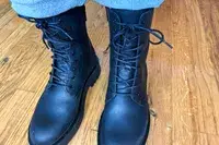 A person stands on a wooden floor while wearing the Thursday Boot Co. Quest Boots