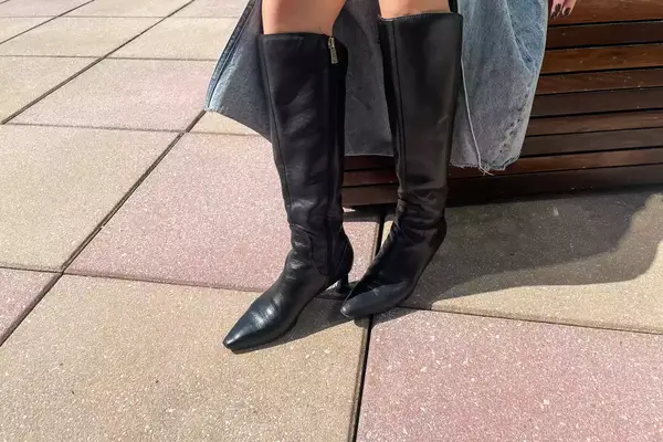A person stands outside while wearing the Naturalizer Deesha Knee High Boot
