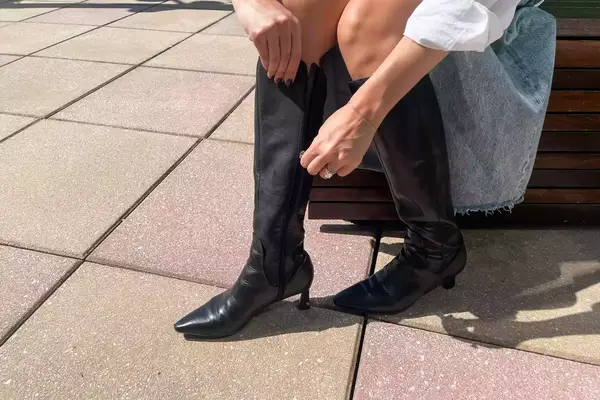 A person zips up the Naturalizer Deesha Knee High Boot