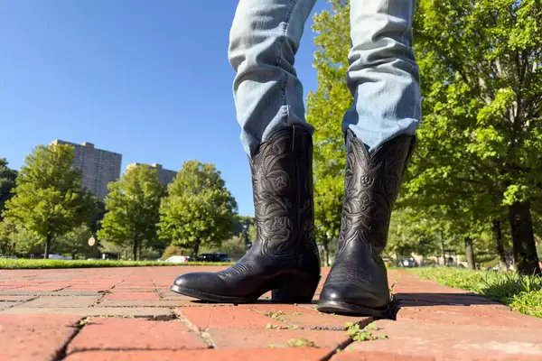 A person wears the Ariat Heritage R Toe Western Boots outside
