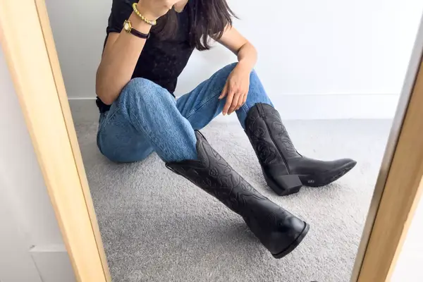 A person sits while wearing the Ariat Heritage R Toe Western Boots