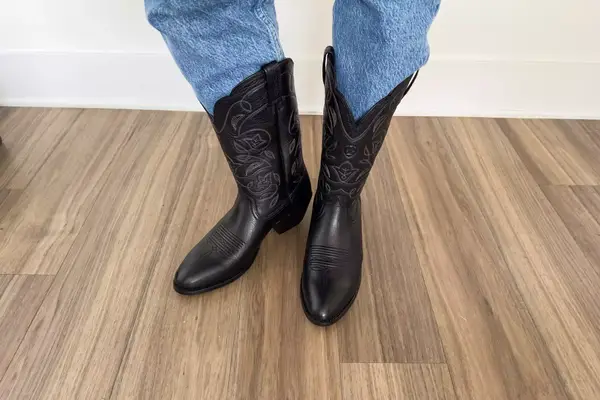 A person wears the Ariat Heritage R Toe Western Boots