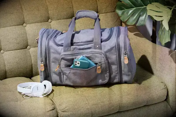 A person zipping up the Gregory Alpaca Duffel 60 on a bed
