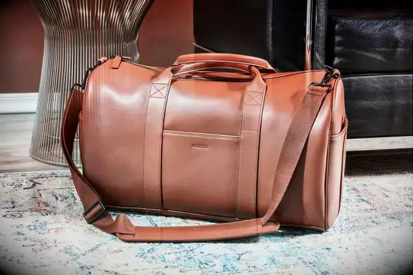 Thule Chasm Sport Duffel Bag on olive couch next to phone and headphones