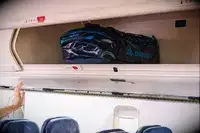 The Gregory Alpaca Duffel 60 in an overhead compartment of a plane