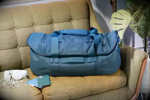 YETI Crossroads Duffel Bag 60L on a couch next to a phone