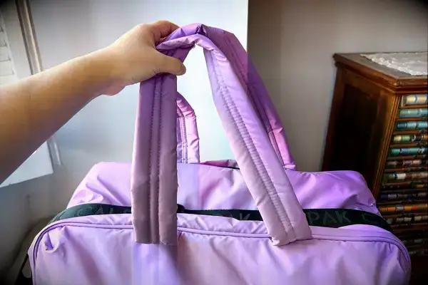 A hand holding the handles of the Calpak Luka Large Duffel