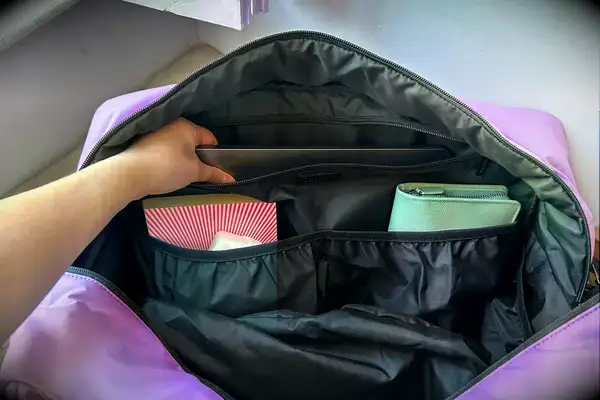 A hand grabbing a laptop in the Calpak Luka Large Duffel