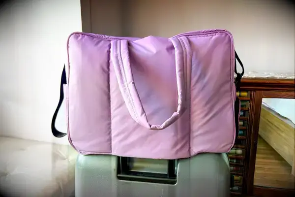 Calpak Luka Large Duffel on top of a suitcase