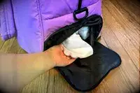 A hand grabbing a shoe out of the Calpak Luka Large Duffel shoe compartment