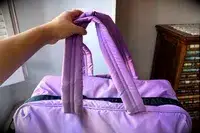 A hand holding the handles of the Calpak Luka Large Duffel