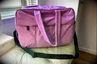 Calpak Luka Large Duffel sitting on a couch