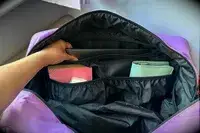 A hand grabbing a laptop in the Calpak Luka Large Duffel