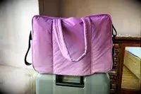 Calpak Luka Large Duffel on top of a suitcase