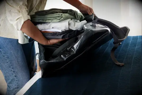 Folded clothing is placed inside the Osprey Transporter Waterproof Duffel 70L