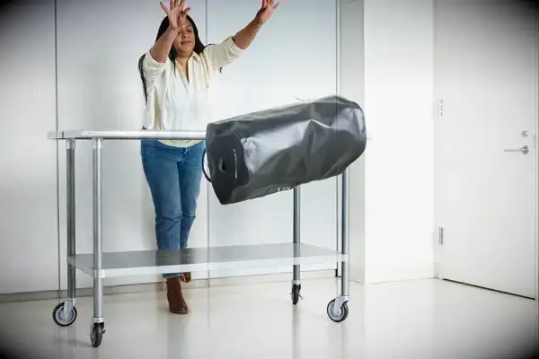 A person throws the Osprey Transporter Waterproof Duffel 70L off of a metal table