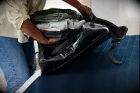 Folded clothing is placed inside the Osprey Transporter Waterproof Duffel 70L